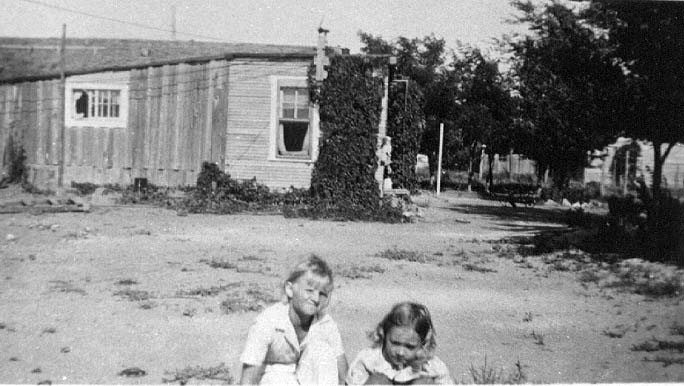 Jean Adrienne playing in front yard of ramon ranch house. A view of the kitchen location is visible from this view.