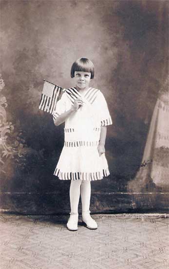 <eddie downer holding an american flag in a studio portrait. Painted background>