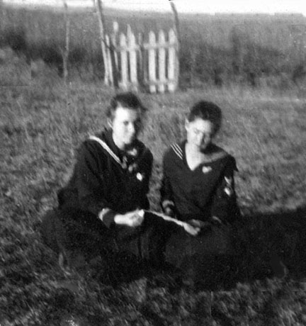 two girls seated in a yard reading a book