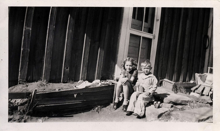 <adrienne and terry sitting on porch on east side of ranch house. may be alan's wheelchair shown in the background>