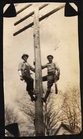 <two men climbing a telephone pole>