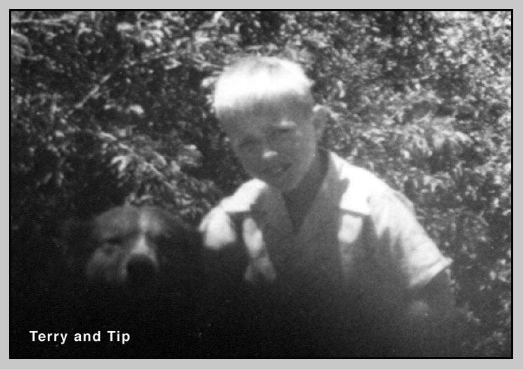 <Terry and Tip in front of plumb bushes behind ranch house>