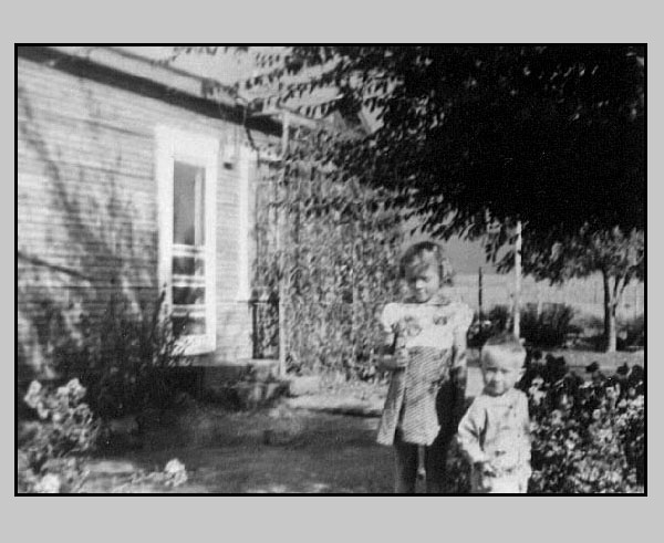 <Adrienne and Terry shown in front yard of ranch house>